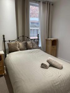 a bed with a towel on it with a window at Rock Lane Rooms in Birkenhead