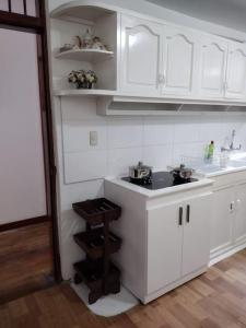 a kitchen with white cabinets and a sink at Acogedor Departamento Central in Loja