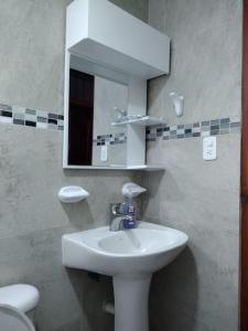 a bathroom with a sink and a mirror and a toilet at Acogedor Departamento Central in Loja