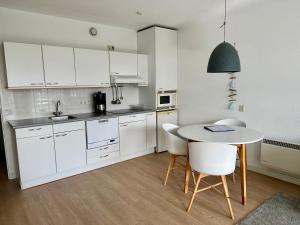 a kitchen with white cabinets and a table and chairs at Appartement Badhotel 325 in Callantsoog