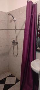 una ducha con cortina púrpura junto a un lavabo en Riad Dar Tazoulte, en Agdz