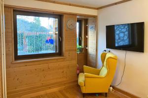 a living room with a yellow chair and a television at Chalet Erika: che vista! in San Martino di Castrozza