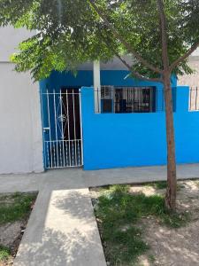 a blue building with a gate and a tree at Magnolia Departamento/Apartment in Barrio Esteban Echeverría