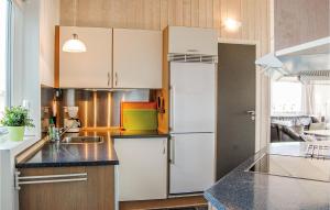 a kitchen with white cabinets and a refrigerator at Stunning Home In Rudkbing With Sauna in Spodsbjerg