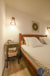 a bedroom with a bed and a table with a night stand at 365 Guest House in Hunedoara