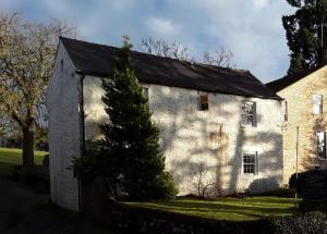 a white building with a tree in front of it at The Coach House at Lowbyer in Alston