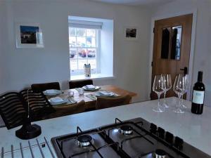 a kitchen with a stove and a table with wine glasses at The Coach House at Lowbyer in Alston