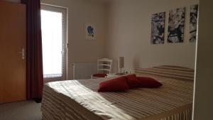 a bedroom with a bed with a red pillow on it at Haus Lieberum Ferienwohnung 1.Etage Balkon in Bad Sooden-Allendorf