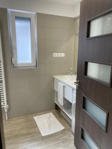 a bathroom with a sink and a toilet and a door at RoyalHill Apartman in Vonyarcvashegy +11 photos