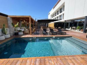 a swimming pool with a wooden deck and a building at Alto del Sol Latorre Mejillones in Mejillones