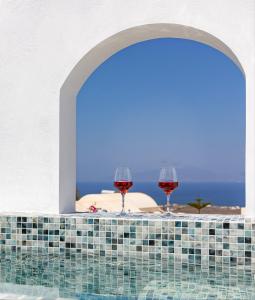 two glasses of wine sitting on a table with the ocean in the background at Theophrasti Suites in Foinikiá