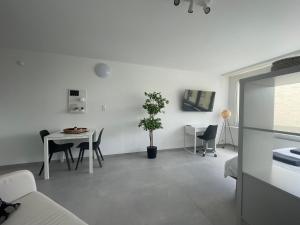 a white living room with a table and a chair at H95 Studios in Basel City with Basel Card in Basel