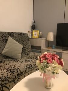 een woonkamer met een bank en een vaas met bloemen bij Macanese Elegant Retreat with Fantastic View of HK Zhuhai Macau Bridge in Macau