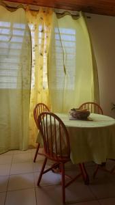 a table with two chairs and a white table and two windows at Studio La villa du Manguier in Le Vauclin