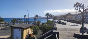 uma praia com palmeiras e o oceano e um calçadão em Terraza del sol em Candelaria