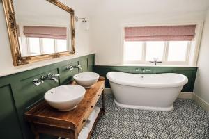 y baño con 2 lavabos, bañera y espejo. en Luxury Farm Cottage with Hot Tub, en Northallerton