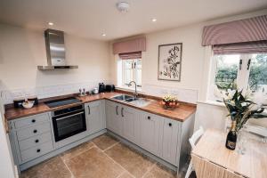 una cocina con armarios blancos y fregadero en Luxury Farm Cottage with Hot Tub, en Northallerton