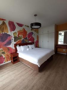 een slaapkamer met een bed en een schilderij aan de muur bij The Oceanic Self Catering Apartment in Durban