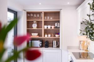 a kitchen with a shelf with cups and a microwave at Elegant 3 bedroom home in the centre of Cheltenham in Cheltenham