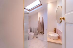 a bathroom with a sink and a toilet and a skylight at Elegant 3 bedroom home in the centre of Cheltenham in Cheltenham