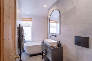 a bathroom with a tub and a sink and a mirror at Elegant 3 bedroom home in the centre of Cheltenham in Cheltenham