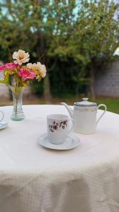 une table avec deux tasses et un vase de fleurs dans l'établissement Dunas Doradas, à Tinogasta