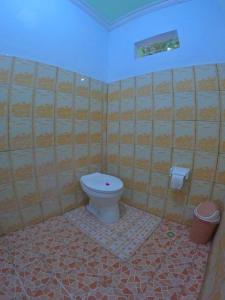 a bathroom with a toilet and a tiled wall at Mango Homestay in Sekotong