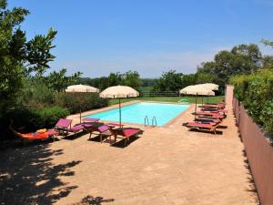 a swimming pool with lounge chairs and umbrellas at Chic Farmhouse in Montalto di Castro with Terrace in Montalto di Castro