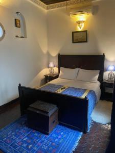 a bedroom with a large bed with a wooden headboard at Charmant Ryad à 1mn de BAB BOUJLOUD DAR SERRAJ in Fez