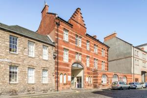 un gran edificio de ladrillo con coches estacionados frente a él en KM Apartments, en Edimburgo