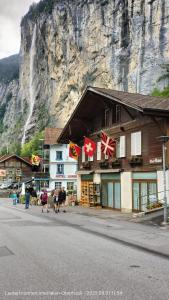 a building with flags on the side of a mountain at Chalet Maithili Lauterbrunnen -152-Year-Old Majestic Chalet in Lauterbrunnen