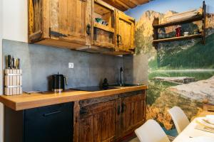 una cocina con armarios de madera y una pintura en la pared en Mountain Shelter by Loft Affair, en Zakopane