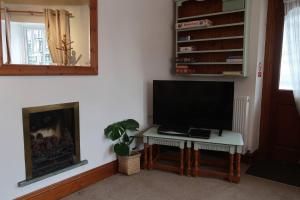 a living room with a television on a table and a fireplace at Cosy 2-bedroom cottage in the Lake District in Bowness-on-Windermere