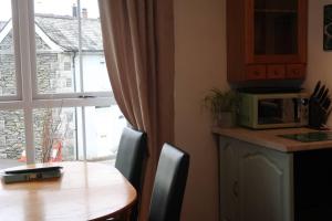 a kitchen with a table and a microwave and a window at Cosy 2-bedroom cottage in the Lake District in Bowness-on-Windermere