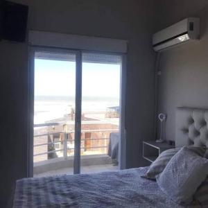 Un dormitorio con una cama y vista al mar. en Cómodo dúplex frente al mar, en Monte Hermoso