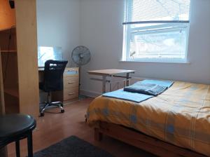 Schlafzimmer mit einem Bett, einem Schreibtisch und einem Fenster in der Unterkunft UnknownRooms in London
