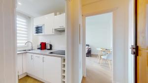 a kitchen with white cabinets and a sink and a table at Sunny City Center in Nice