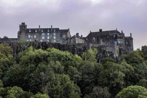 an old castle on top of a hill with trees at City Apartment by the Castle, Free Parking. in Stirling