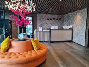 a lobby with an orange couch and a vase with pink flowers at Hotel Fogo Amsterdam in Amsterdam