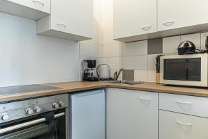 a kitchen with white cabinets and a microwave at Pleasant 2BR Apt- Near Train Station Hetzendorf in Vienna