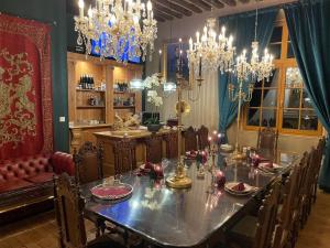 een eetkamer met een lange tafel en kroonluchters bij Chateau Bourgeoisie *** in Laimont