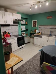 - une cuisine avec des placards blancs et un mur vert dans l'établissement Maison d hôtes Les Notes Endormies " Suite La Mystérieuse", à Berzée