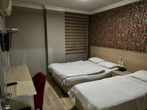 Habitación de hotel con 2 camas, mesa y escritorio en Otel Madi en Seyhan