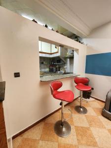 una cocina con 2 sillas rojas y una barra en Winou Surf House, en Aourir