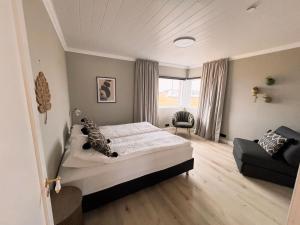 een slaapkamer met een bed, een stoel en een raam bij Garður Apartments in Gardur