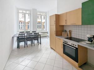 uma cozinha com uma mesa, cadeiras e um fogão em Monteur Dreams - Zentrale, Große Altbauwohnungen, 2 Bäder, Küche em Leipzig