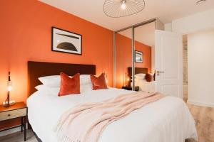 1 dormitorio con 1 cama blanca grande y paredes de color naranja en Modern 2 Bed Apartment, Nightingale Quarter Derby, en Derby