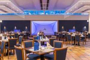 IFA Rügen Hotel & Ferienpark في بينز: غرفة طعام بها طاولات وكراسي وشاشة كبيرة
