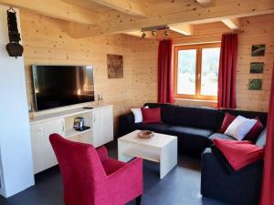 - un salon avec un canapé noir et des fauteuils rouges dans l'établissement Klippitzstern House 2, à Klippitztorl