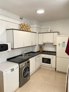 cocina con armarios blancos y lavadora en Apartamento Espert Biescas en Biescas
